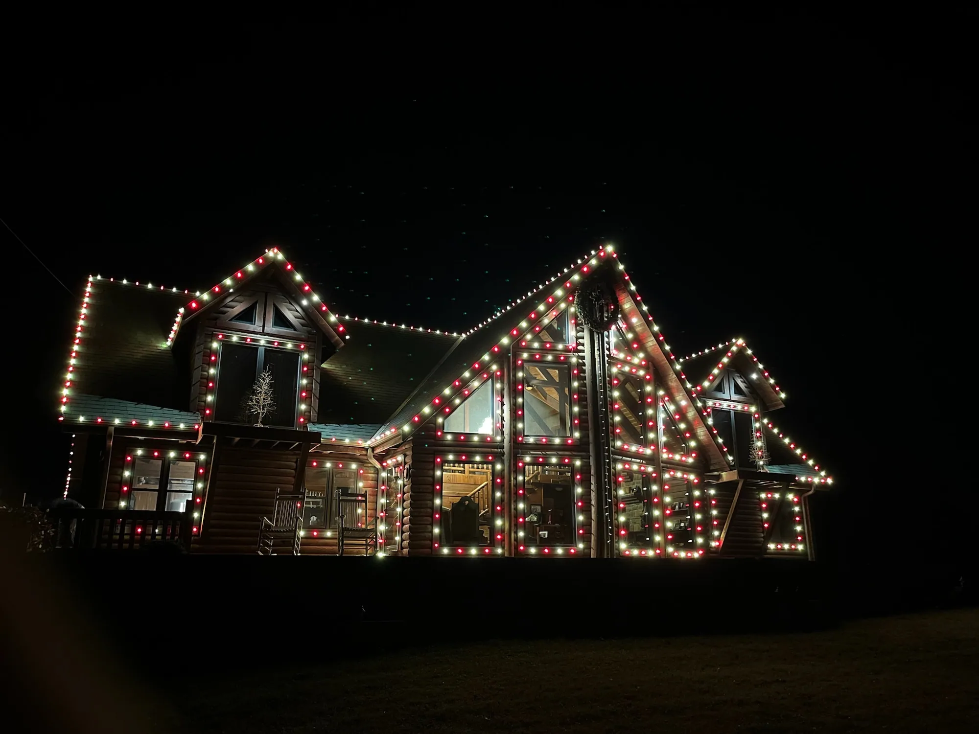 Log cabin outlined in red, white and green. Christmas Lighting by LIT Outdoor Lighting in Tulsa.