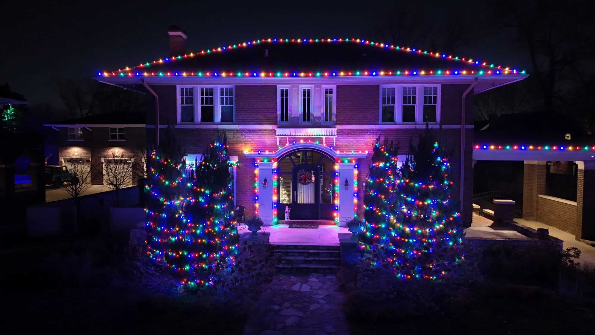 Multicolour roofline over an arched entry. Christmas Lighting by LIT Outdoor Lighting in Tulsa.