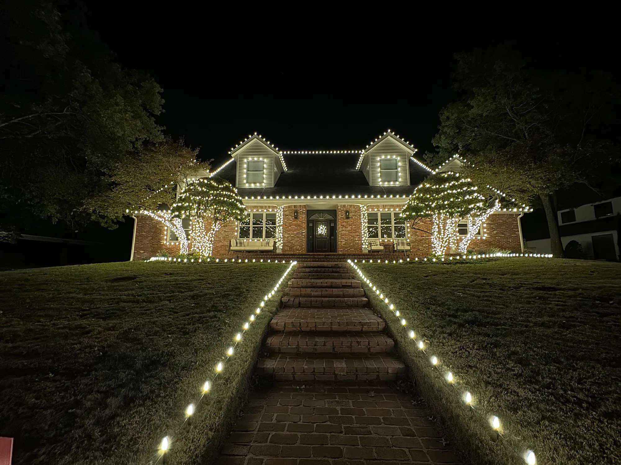 Wrapped trees either side of brick steps. Christmas Lighting by LIT Outdoor Lighting in Tulsa.