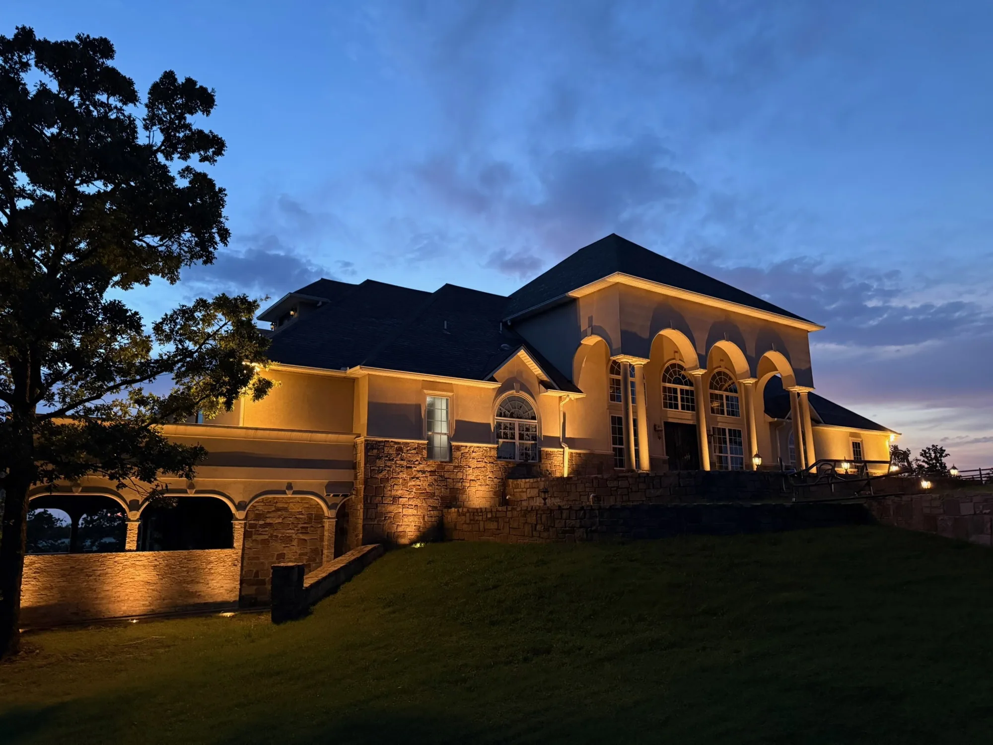 Stone and stucco estate washed at dusk. Landscape Lighting by LIT Outdoor Lighting in Tulsa.