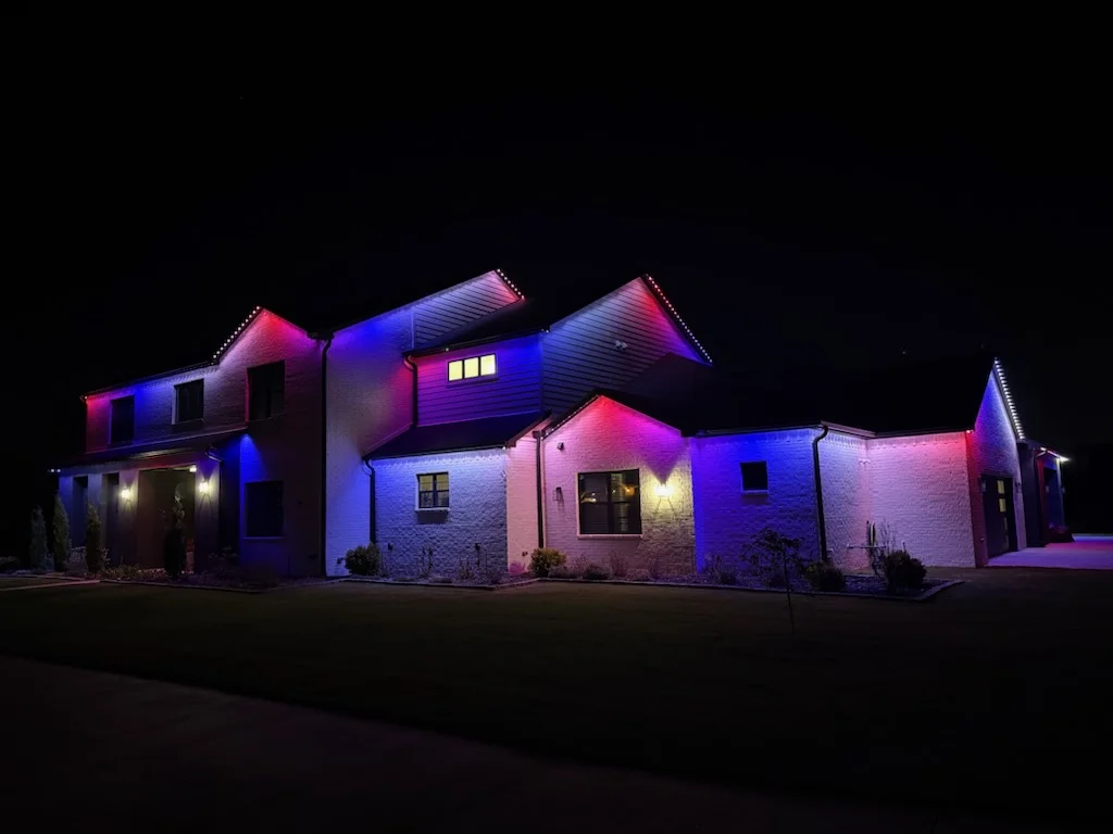 Stone home roofline in blue and magenta. Permanent Lighting by LIT Outdoor Lighting in Tulsa.
