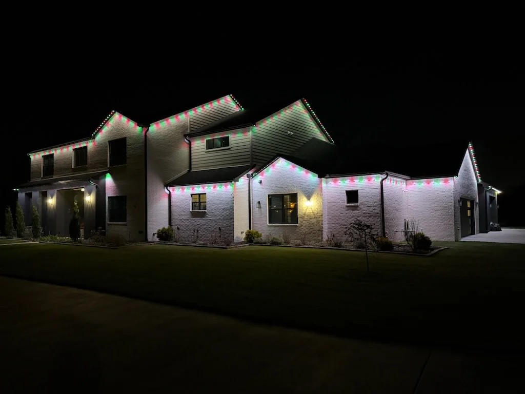 Stone home roofline in red and green. Permanent Lighting by LIT Outdoor Lighting in Tulsa.