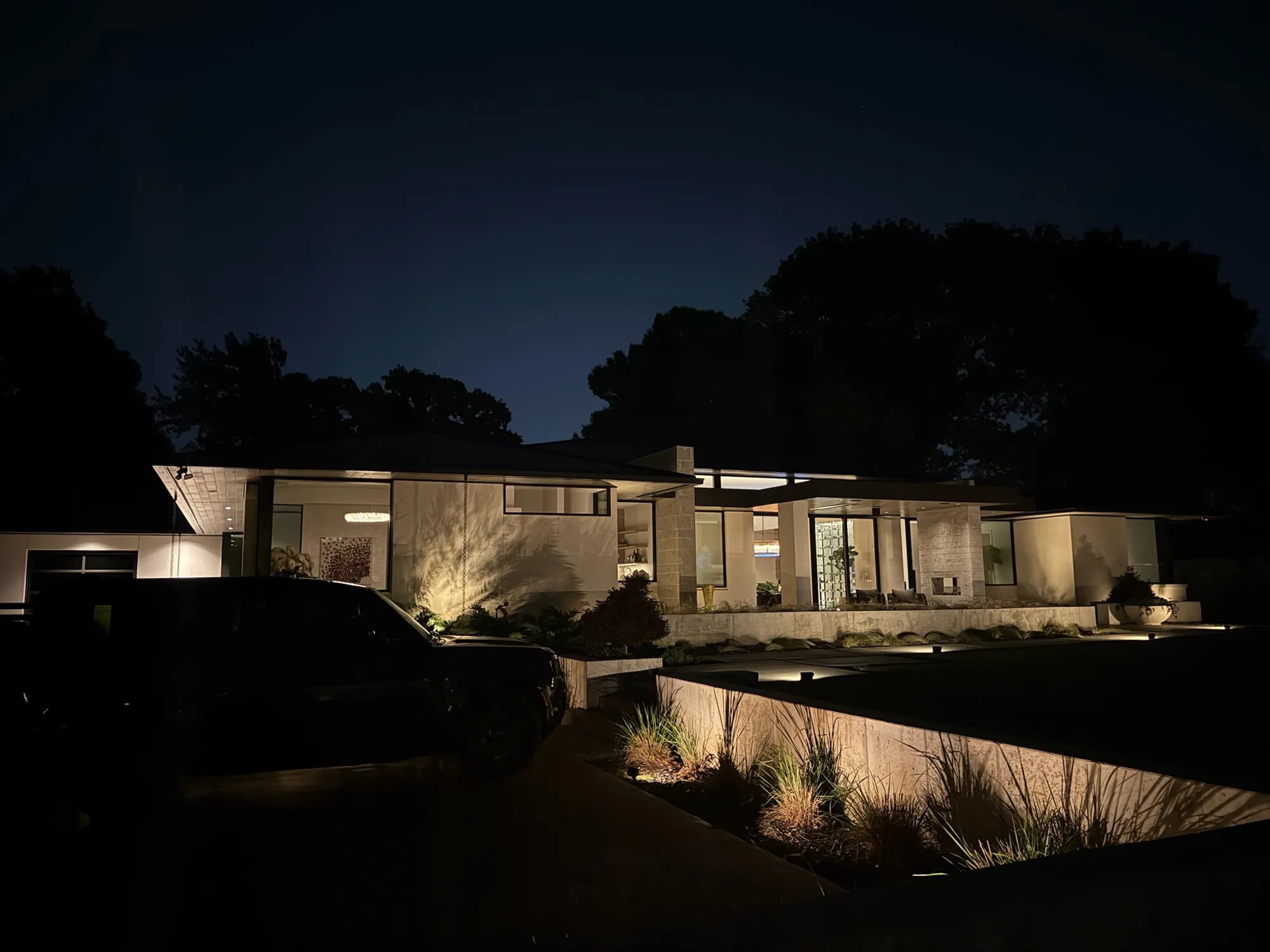 Modern ranch home with lit planting and walls. Landscape Lighting by LIT Outdoor Lighting in Tulsa.