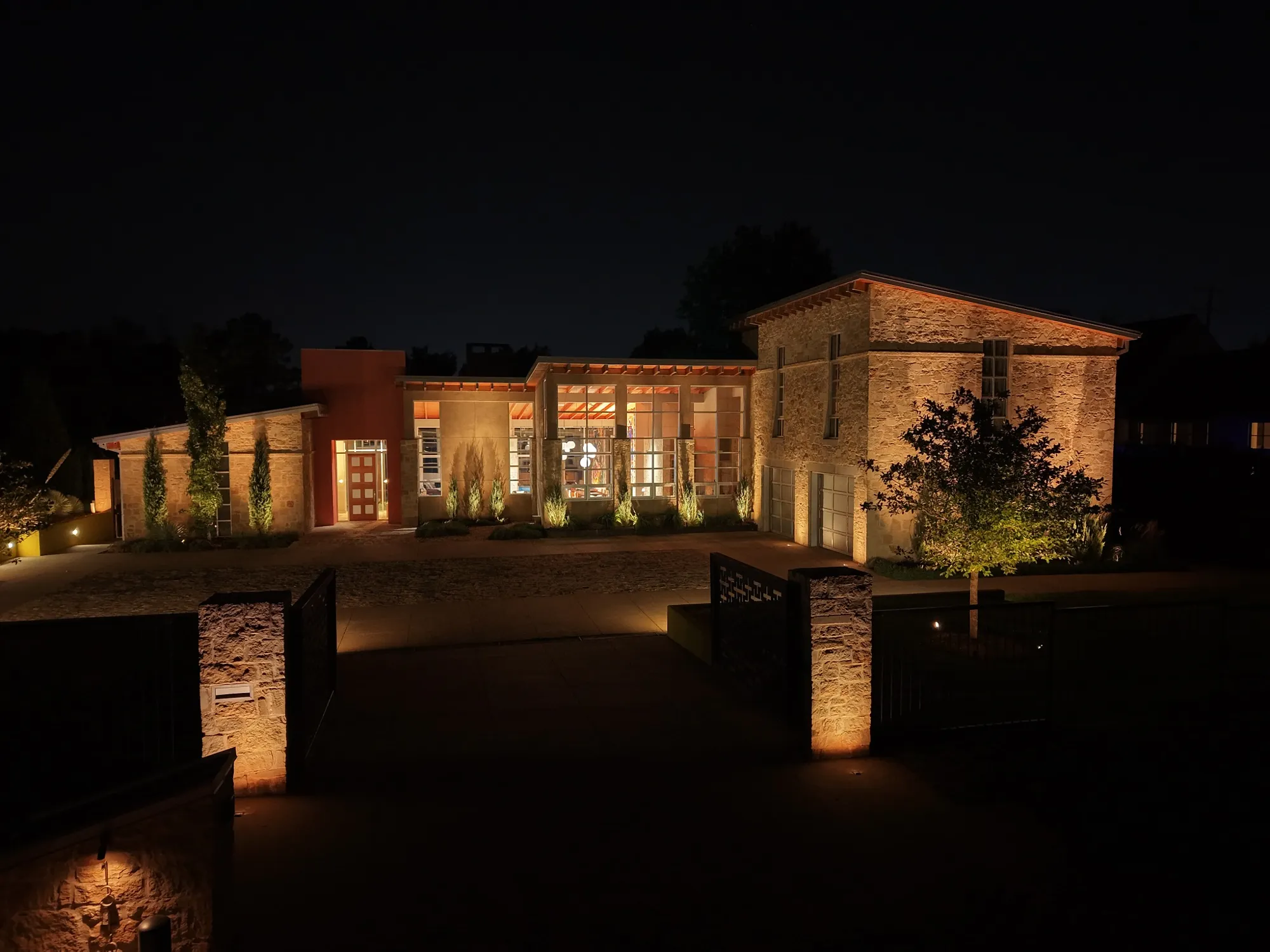 Courtyard stone facade and gate piers lit. Landscape Lighting by LIT Outdoor Lighting in Tulsa.