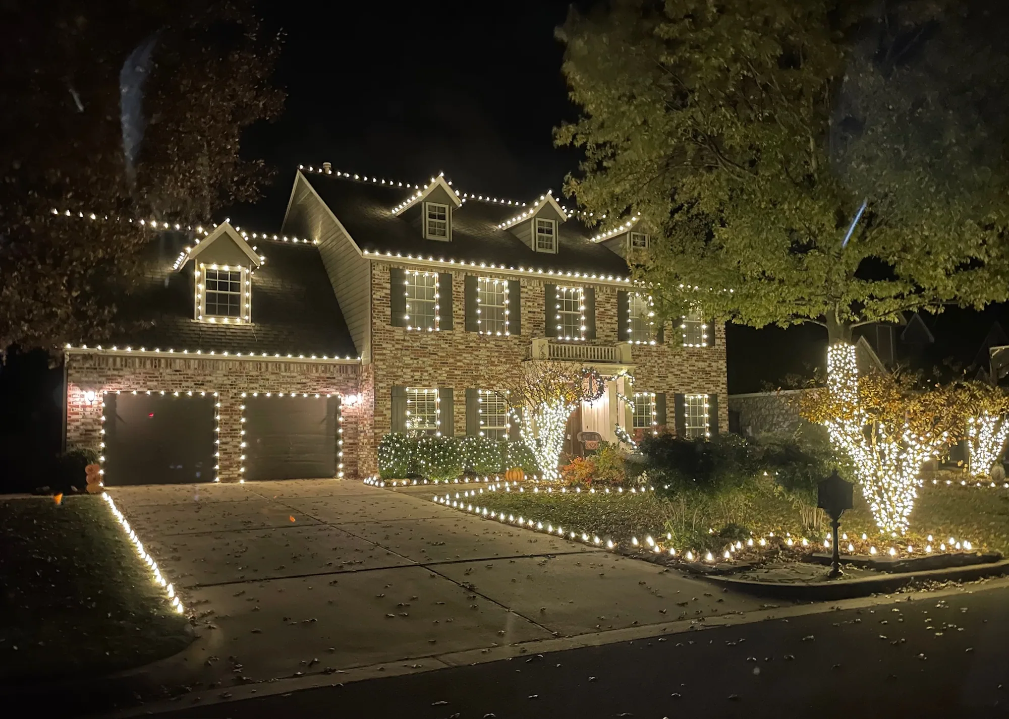 Warm white roofline and an edged driveway. Christmas Lighting by LIT Outdoor Lighting in Tulsa.