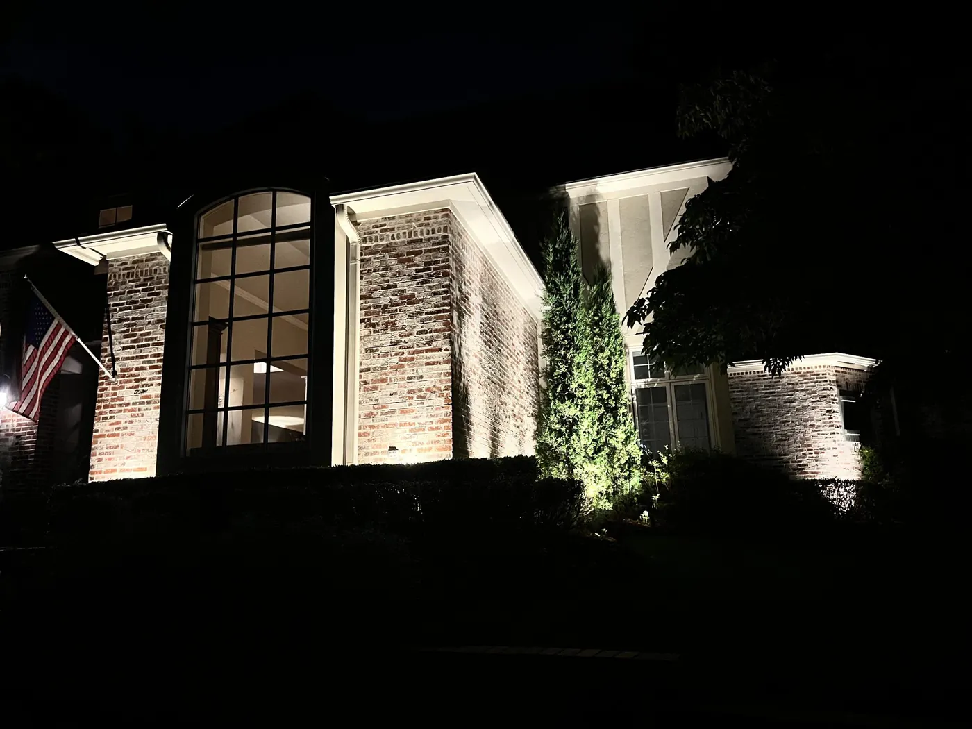 Glass gable end lit from the beds. Landscape Lighting by LIT Outdoor Lighting in Tulsa.