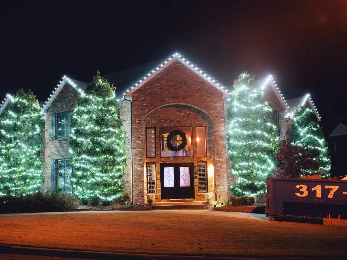 Wreath, garland and two lit firs at the door. Christmas Lighting by LIT Outdoor Lighting in Tulsa.